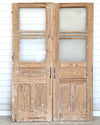 Pair of wooden doors with glass panels against a white wall.