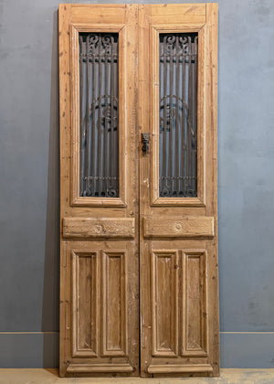 Wooden double door with metal grille on a gray background