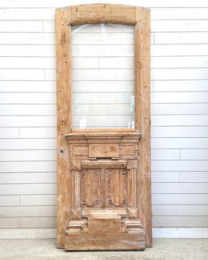 Vintage wooden door with glass panel against a white paneled wall