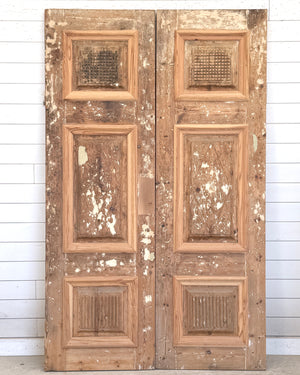 Vintage wooden panel doors with a distressed finish against a white paneled wall.