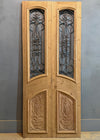 Wooden door with glass panels and decorative carvings on a gray background