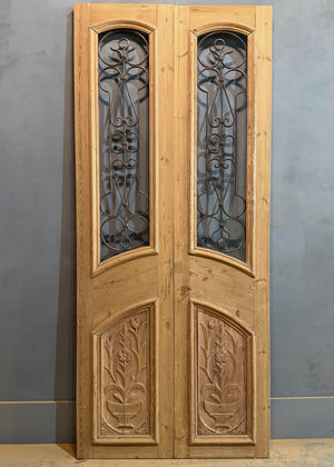 Wooden door with glass panels and decorative carvings on a gray background