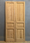 Pair of wooden doors with panel design against a gray wall.