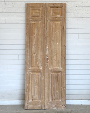 Pair of wooden doors against a white paneled wall