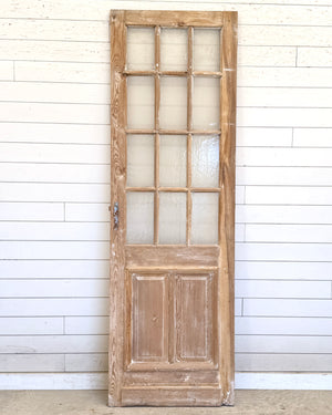 Vintage wooden door with glass panels against a white paneled wall