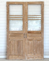 Pair of wooden doors with glass panels against a white wooden panel background