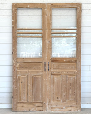 Pair of wooden doors with glass panels against a white wooden panel background